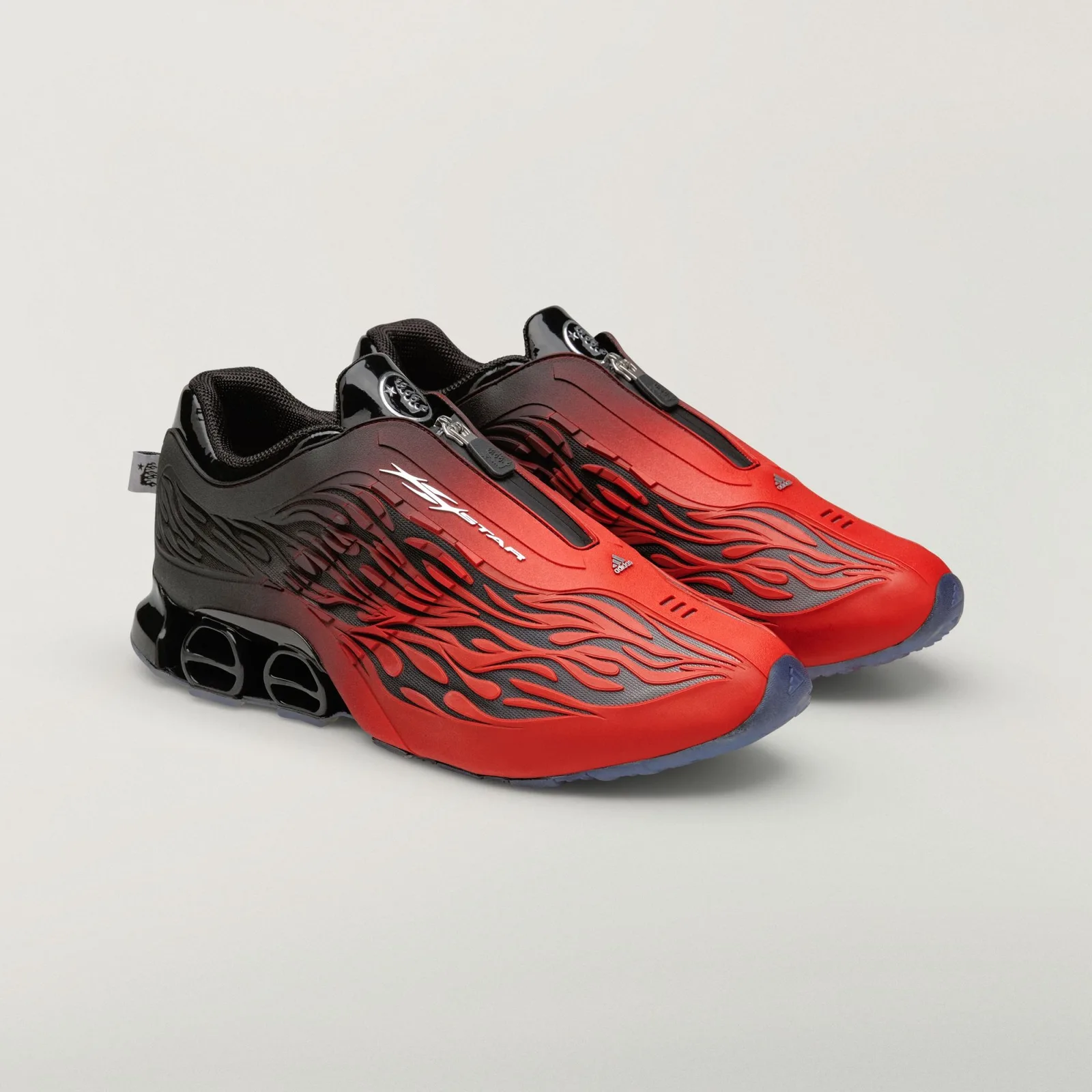 Pair at three-quarter angle, red-to-black fade, front zips, silver round badges, clear blue outsoles, Red/Black