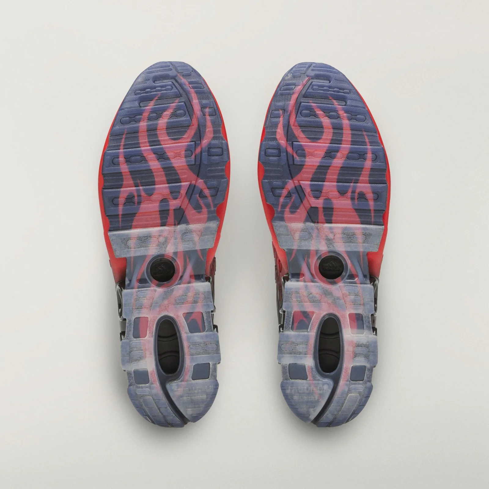 Outsole view of pair, translucent blue-grey tread with red flame graphics and round black heel cutouts, Red/Black