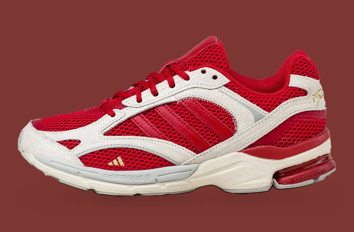 Lateral view on maroon backdrop, red mesh upper, cracked white overlays, gold logo, adiPRENE text, x Tyrrell Winston