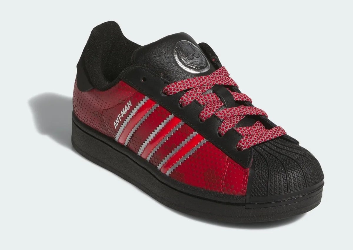 Front three-quarter view with red textured panels and a black shell toe, adidas Superstar “Ant Man”