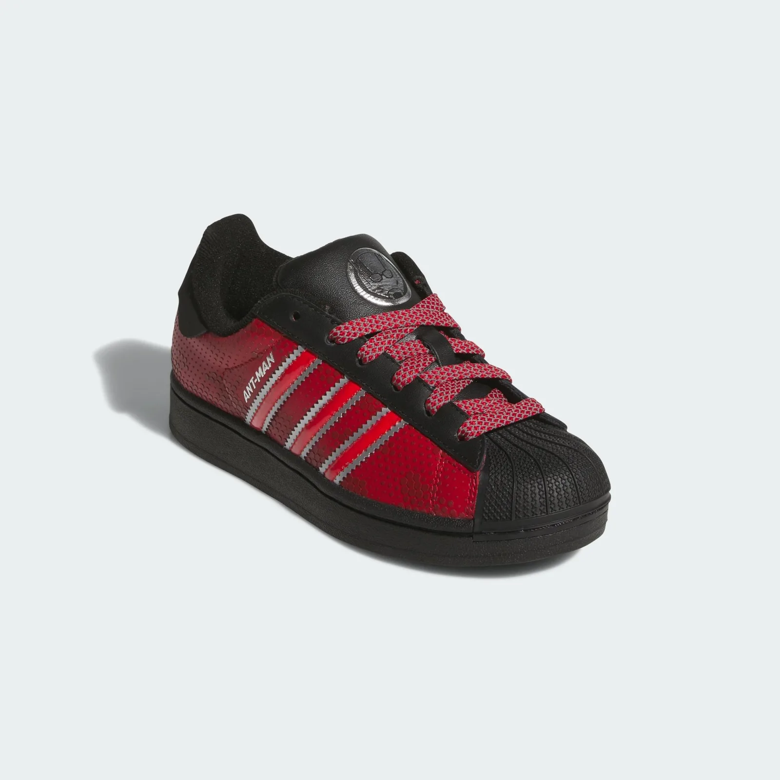 Front three-quarter view with patterned red laces and a silver tongue emblem, Ant Man
