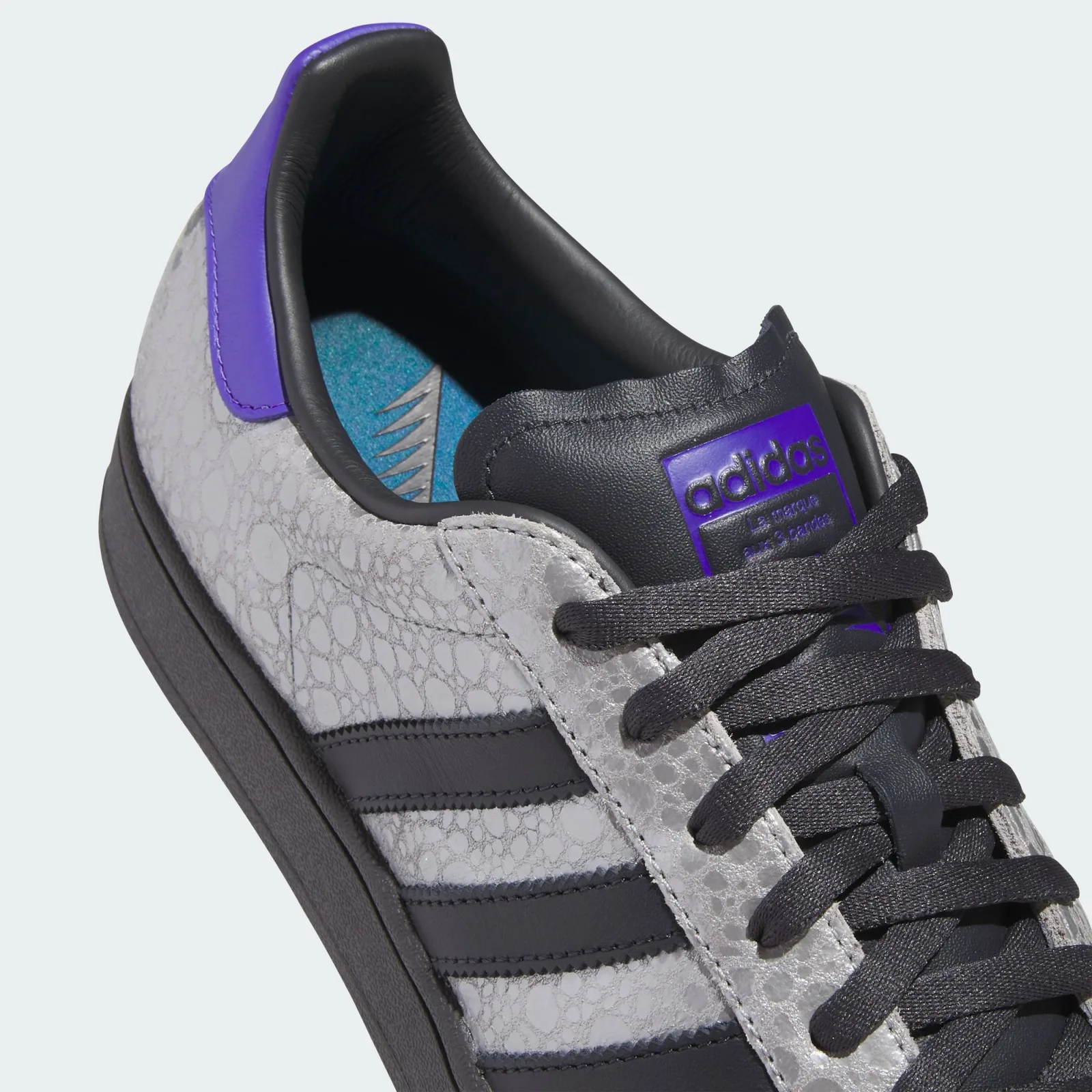 heel detail close-up, purple pull tab, black adidas patch, teal insole edge, Stone