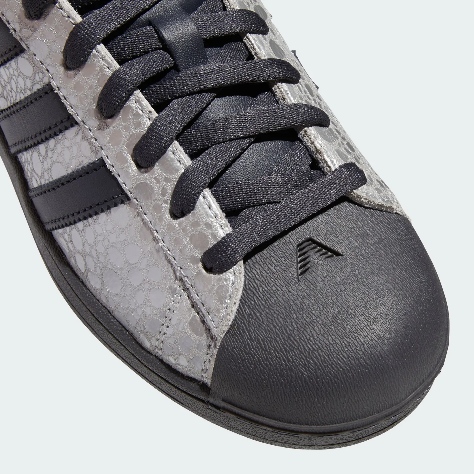 toe detail close-up, black toe cap with small logo, dark laces, cracked texture, Stone