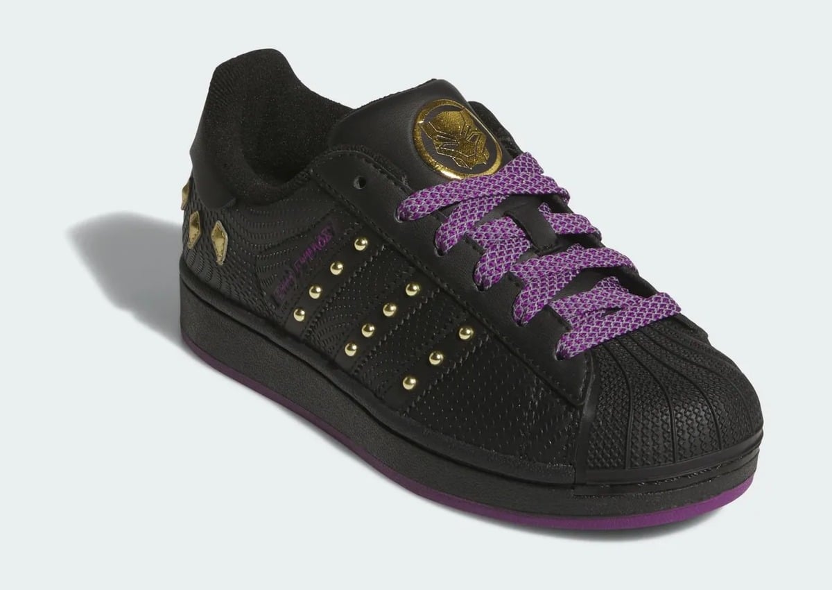 Front three-quarter view with purple laces and gold studs on black stripes, adidas Superstar x Marvel “Black Panther”