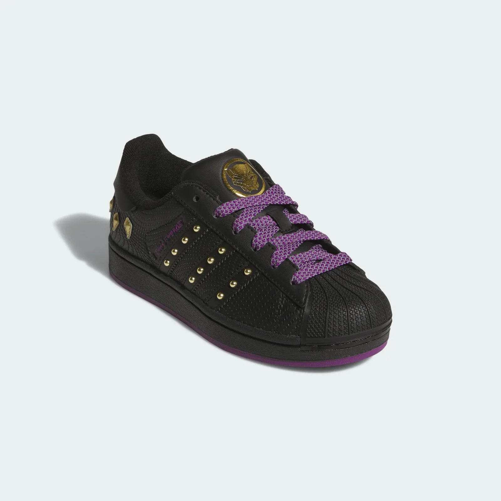 Front three-quarter view with a black shell toe and gold Black Panther tongue logo, Black Panther