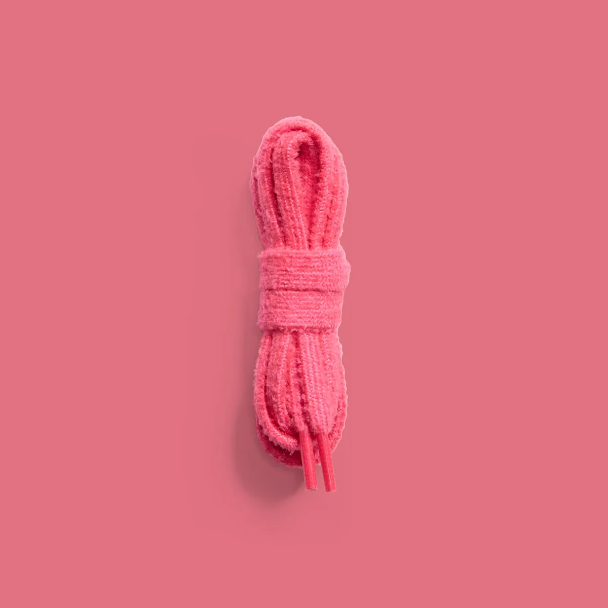 Coiled fuzzy pink shoelaces on a matching pink background, flat-lay, Lola Bunny