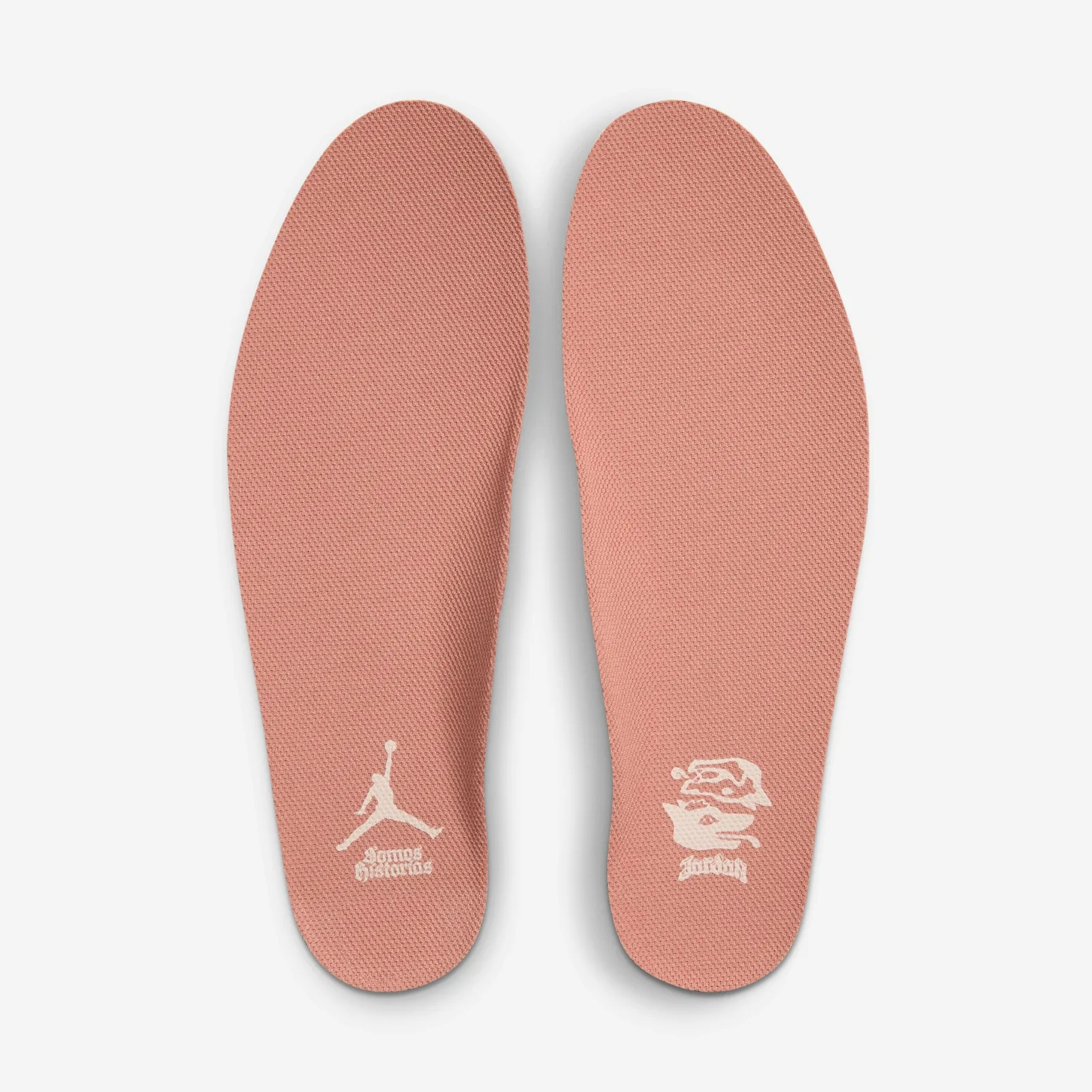 Pair of pink insoles with cream Jumpman and Somos Historias lettering, plus a face graphic, Somos Historias