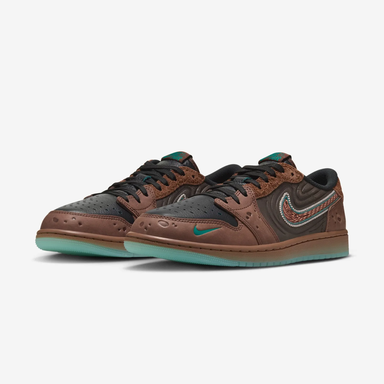 Pair at three-quarter angle, cratered brown toes, black laces, small teal swoosh, icy sole, Somos Historias
