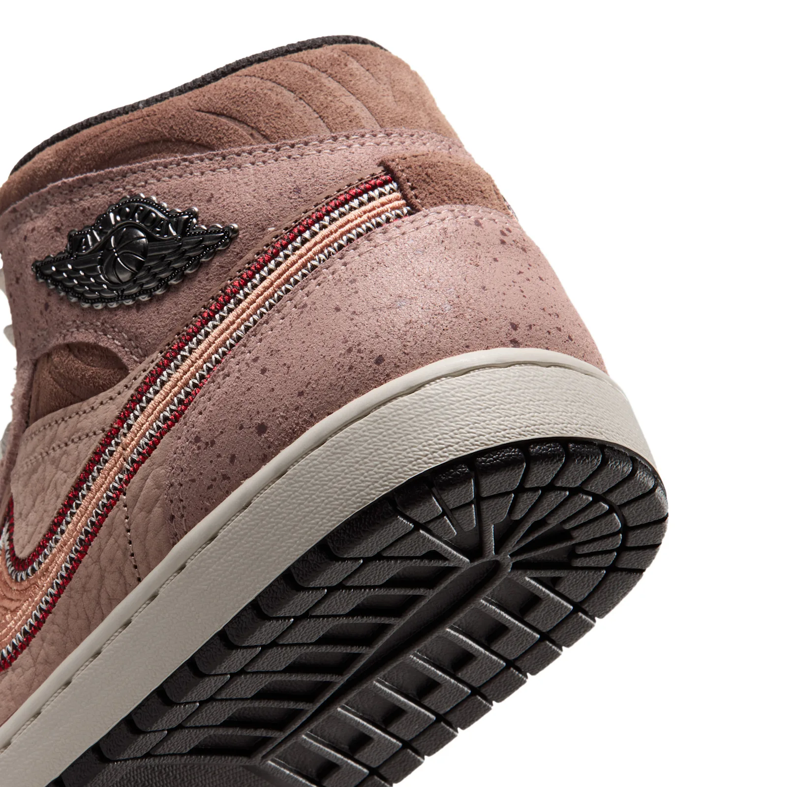 Detail of heel and outsole, silver wings badge, red and peach stitched swoosh, speckled pink suede, Dia de Los Muertos