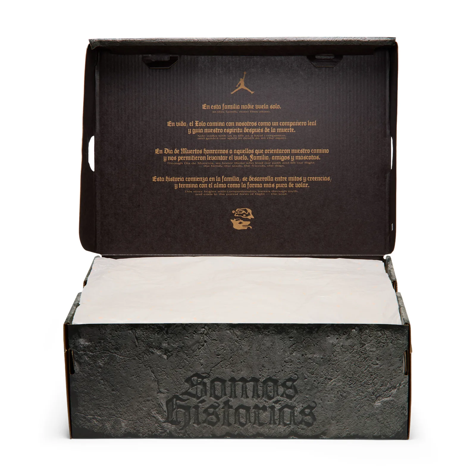 Open box with tissue, gold Spanish and English text on lid, stone-textured Somos Historias lid, Dia de Los Muertos