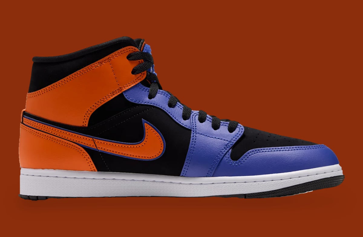 Medial view, orange swoosh on black panel, blue toe and orange heel, rust backdrop, Knicks