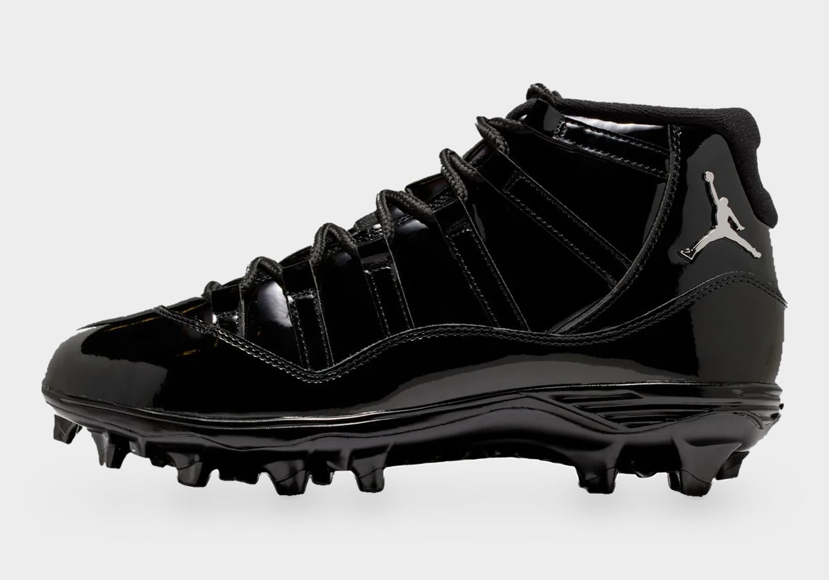 Lateral view of black patent leather cleat with silver Jumpman logo on the heel and molded studs, Gammas