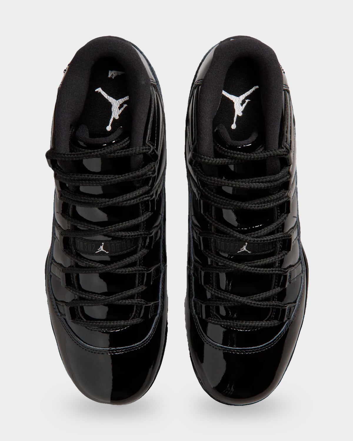 Top-down view of pair, black patent uppers, black laces and white Jumpman logos on the tongues, Gammas