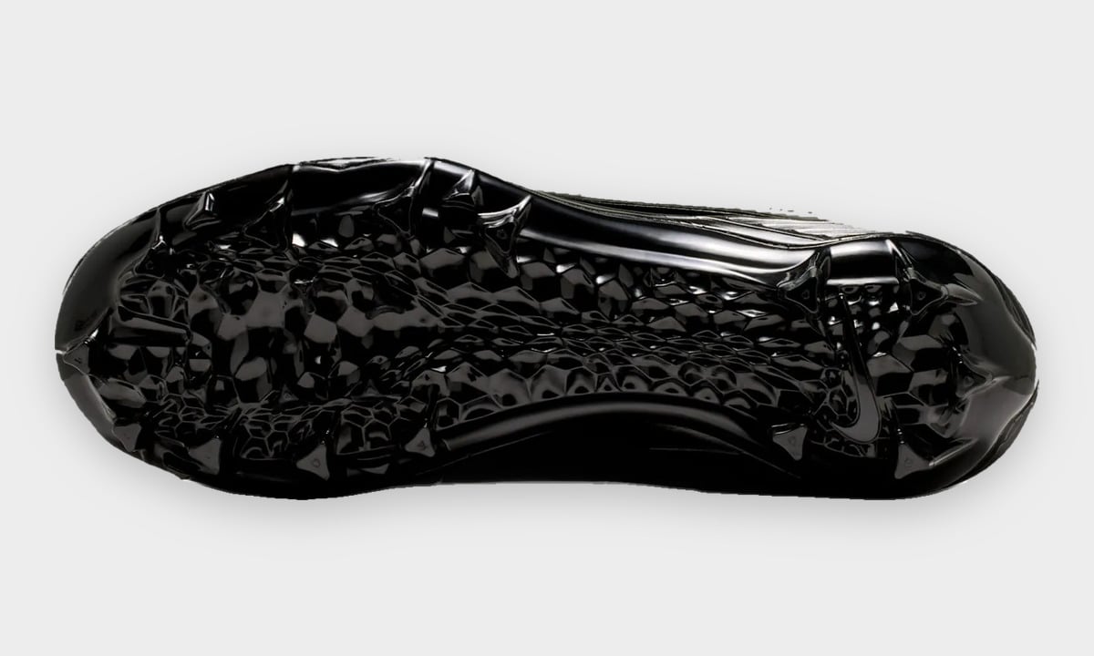 Outsole view of black cleat with textured honeycomb-style traction pattern and studs, Gammas
