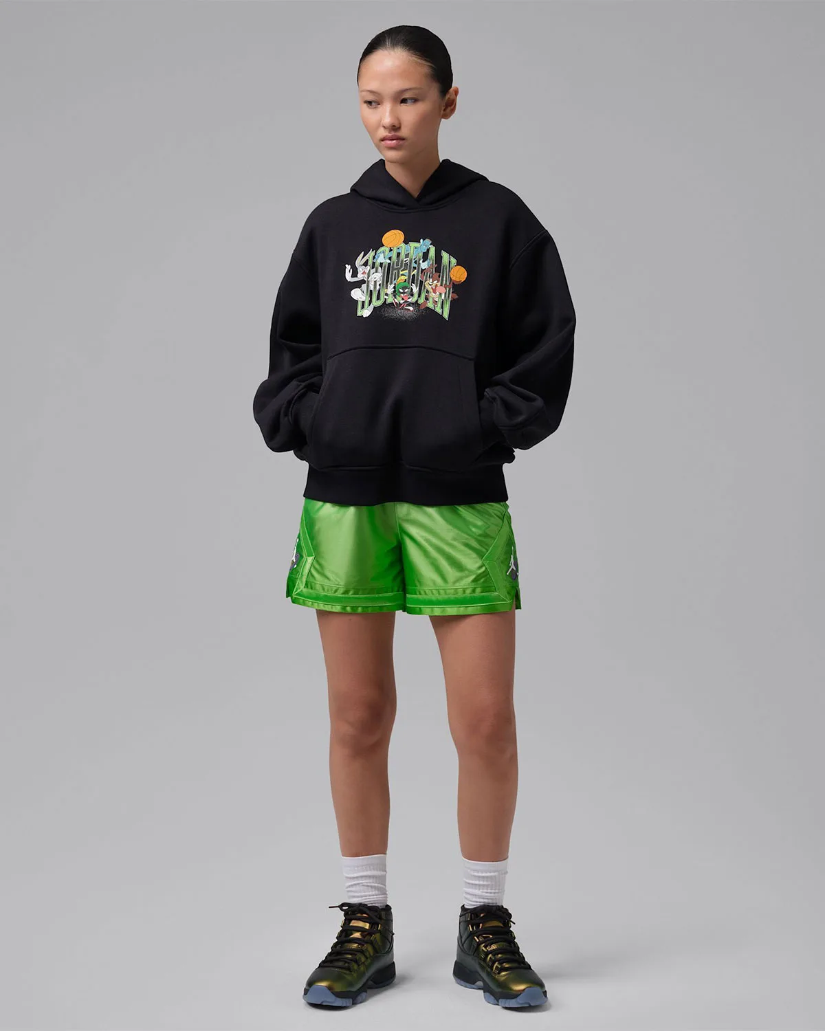 full-body on-foot, pair of iridescent gold high-top sneakers with black graphic hoodie and green shorts, WMNS Space Jam