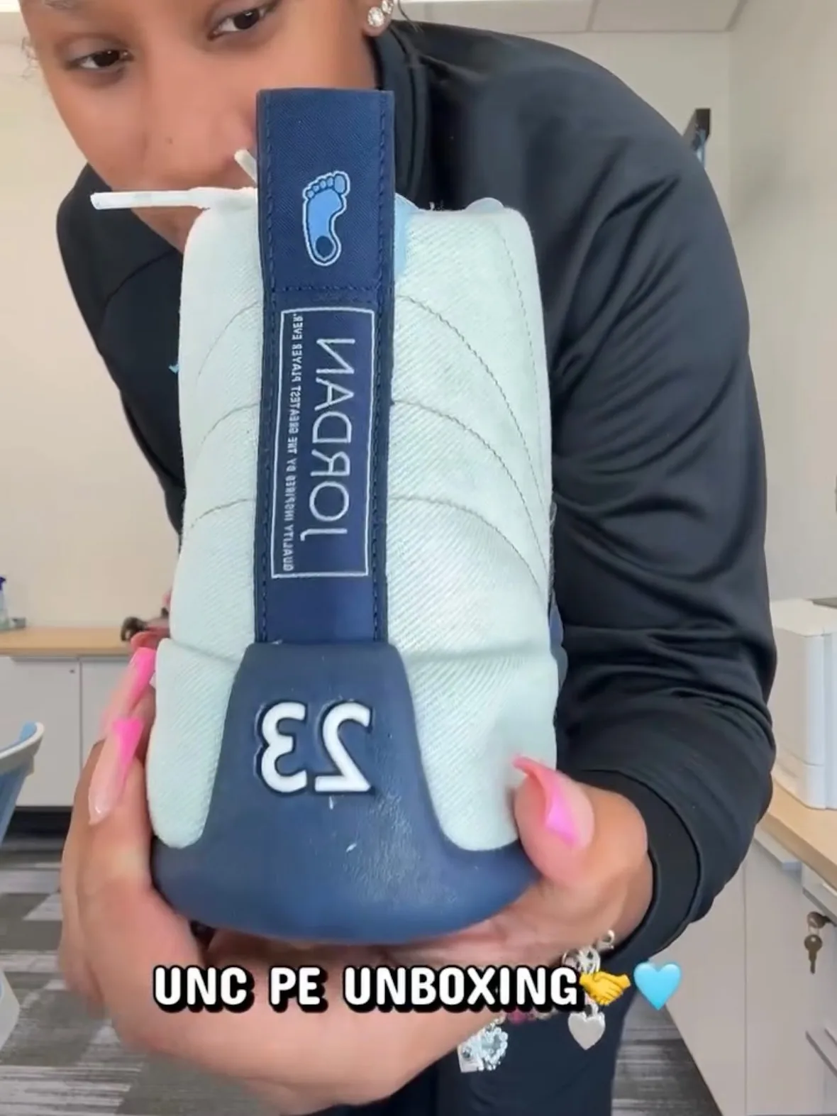 In-hand heel view, mirrored: navy tab with footprint logo, Jordan text and 23, UNC