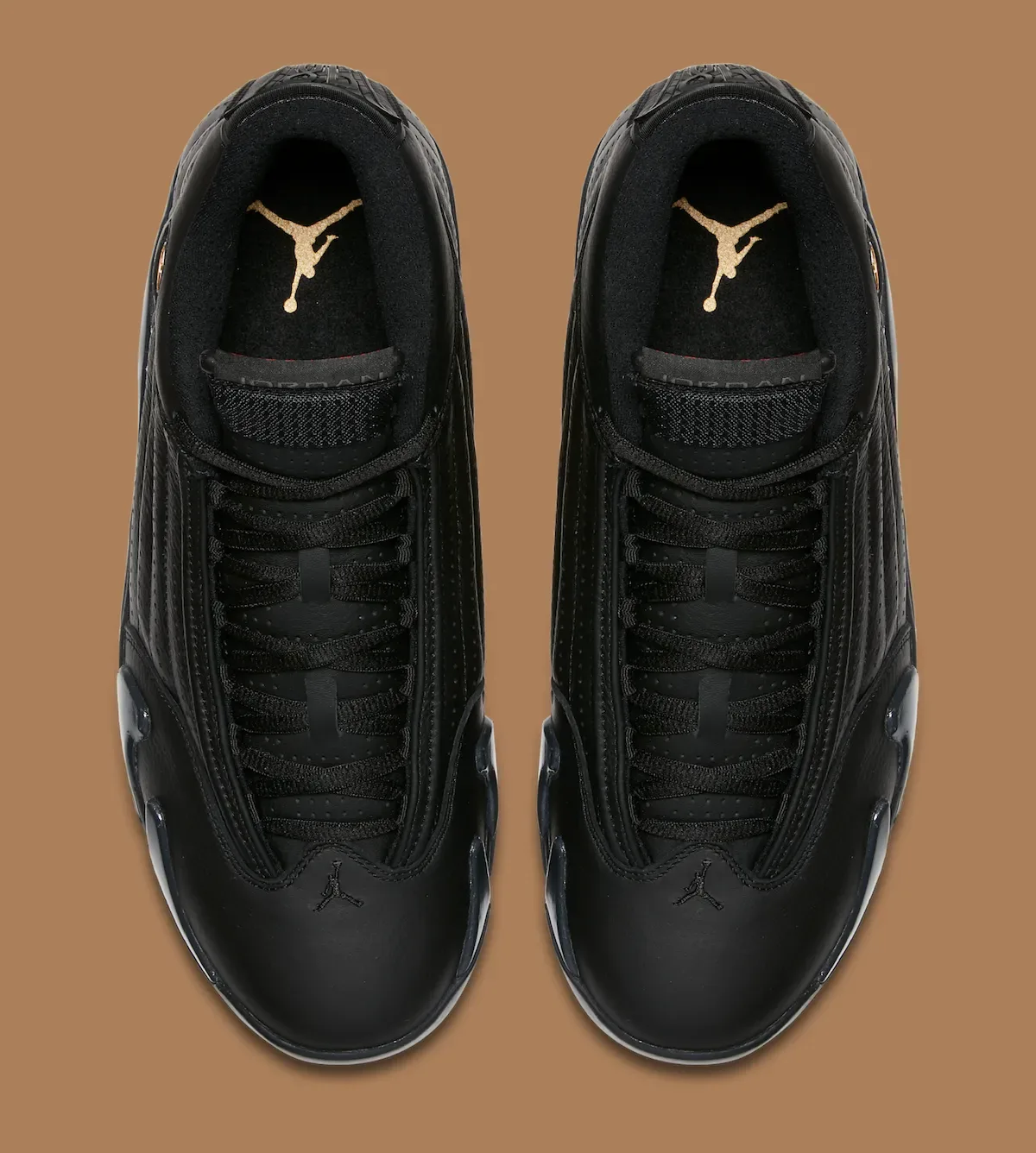 Top-down view of black sneakers with gold Jumpman logos on insoles on brown background, Defining Moments Pack