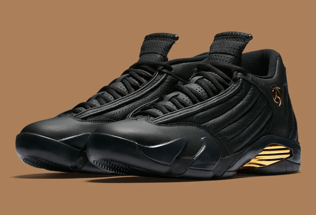 Pair of black leather sneakers with gold shield logos and gold heel inserts on brown background, Defining Moments Pack