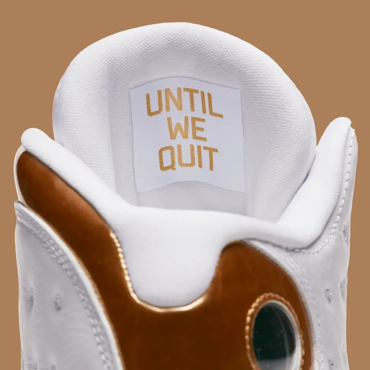 Detail of white shoe collar with gold 'Until we quit' label and glossy gold heel panel, Defining Moments Pack
