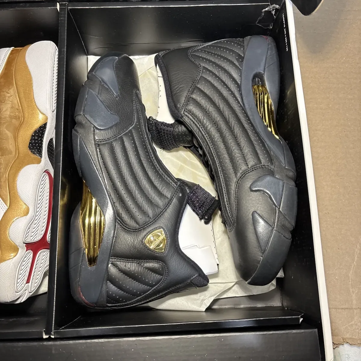 Black quilted leather sneakers with gold shield badge and gold heel inserts, in a box with tissue, Defining Moments Pack
