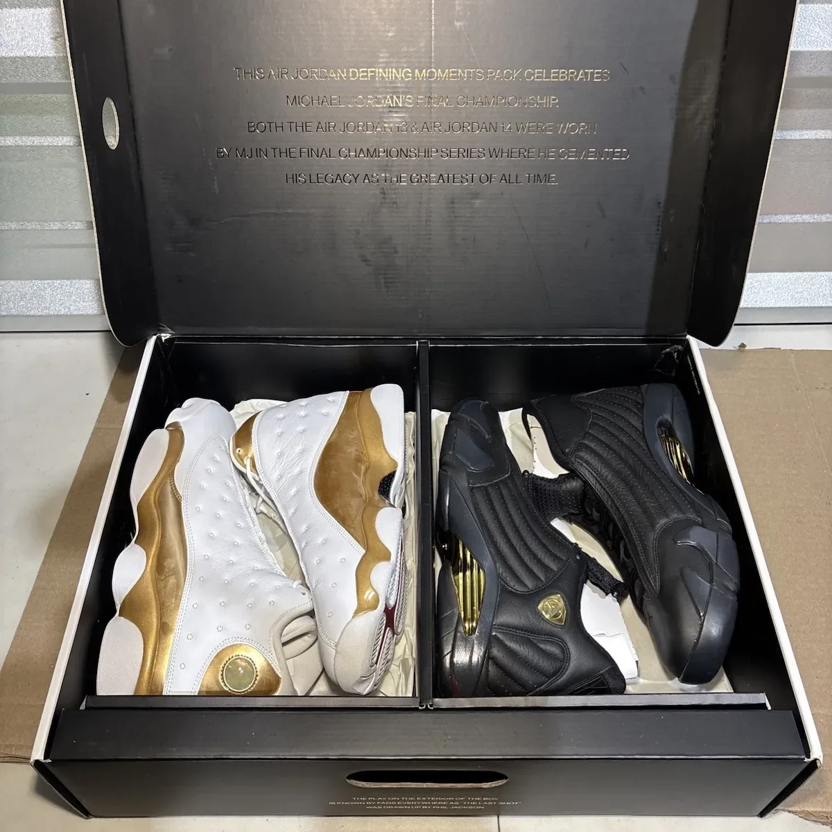 Open box lid with gold text above white-gold and black-gold sneaker pairs on tissue paper, Defining Moments Pack