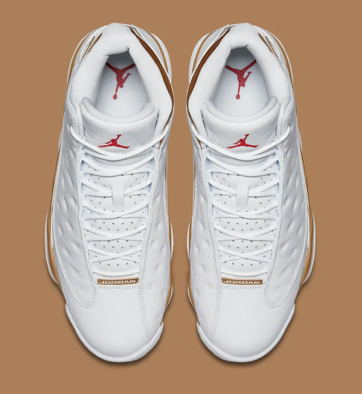 Top-down view of white sneakers with red Jumpman logos and gold JORDAN tags on brown background, Defining Moments Pack