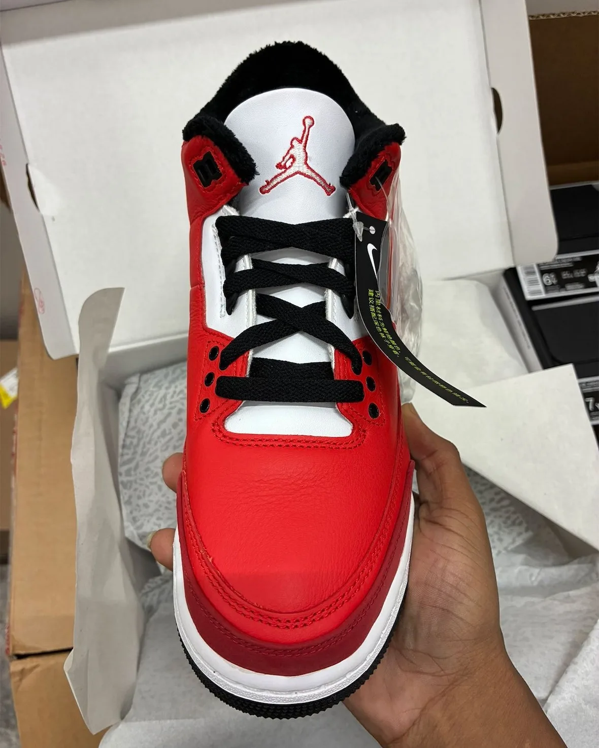 Top-down view of laces and tongue, white Jumpman tongue logo, black laces, red leather toe, hang tag, Santa