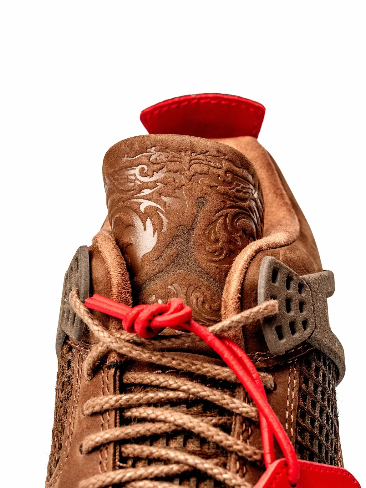 Detail of laser-etched tongue with scrollwork, red pull tab, red cord knot and laces, Bin23