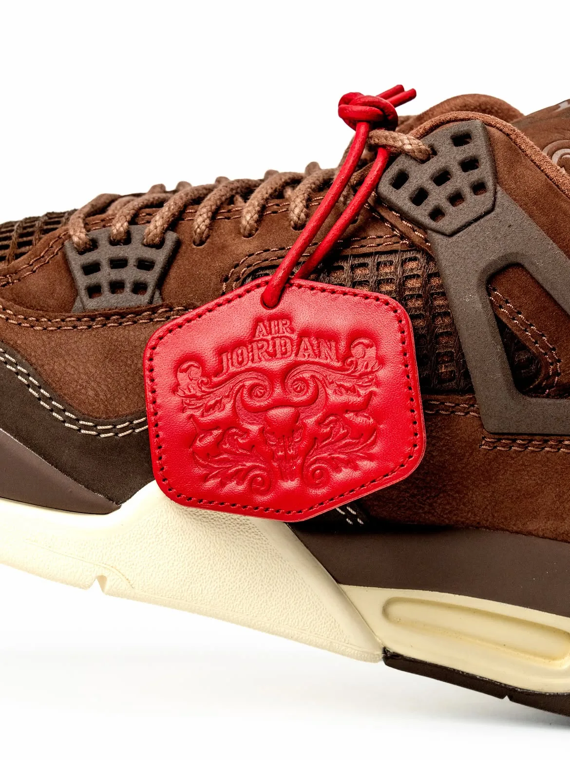 Close lateral detail of red leather Air Jordan tag with skull emboss on brown shoe, Bin23