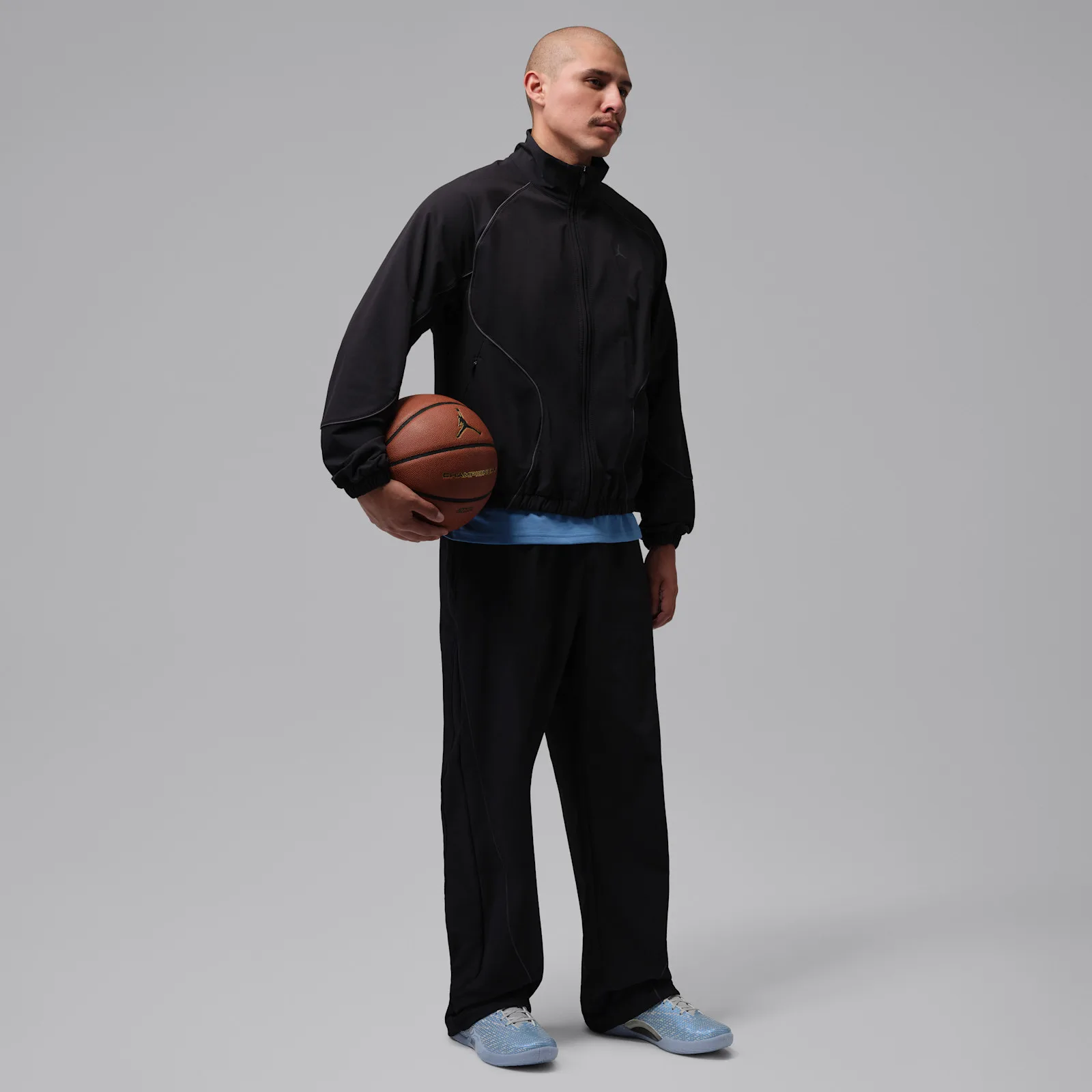 On-foot view, person in black jacket and trousers holding a basketball, light blue shoes, Space Jam