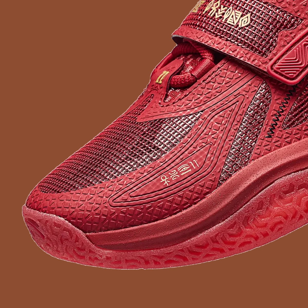 Toe detail, red textured overlays, gold glyphs on strap and red patterned sole, Red