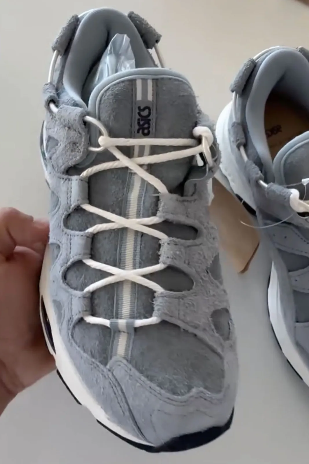 Top-down in-hand view, blue-grey suede cutout upper, white laces and striped tongue, x Giorgio Armani