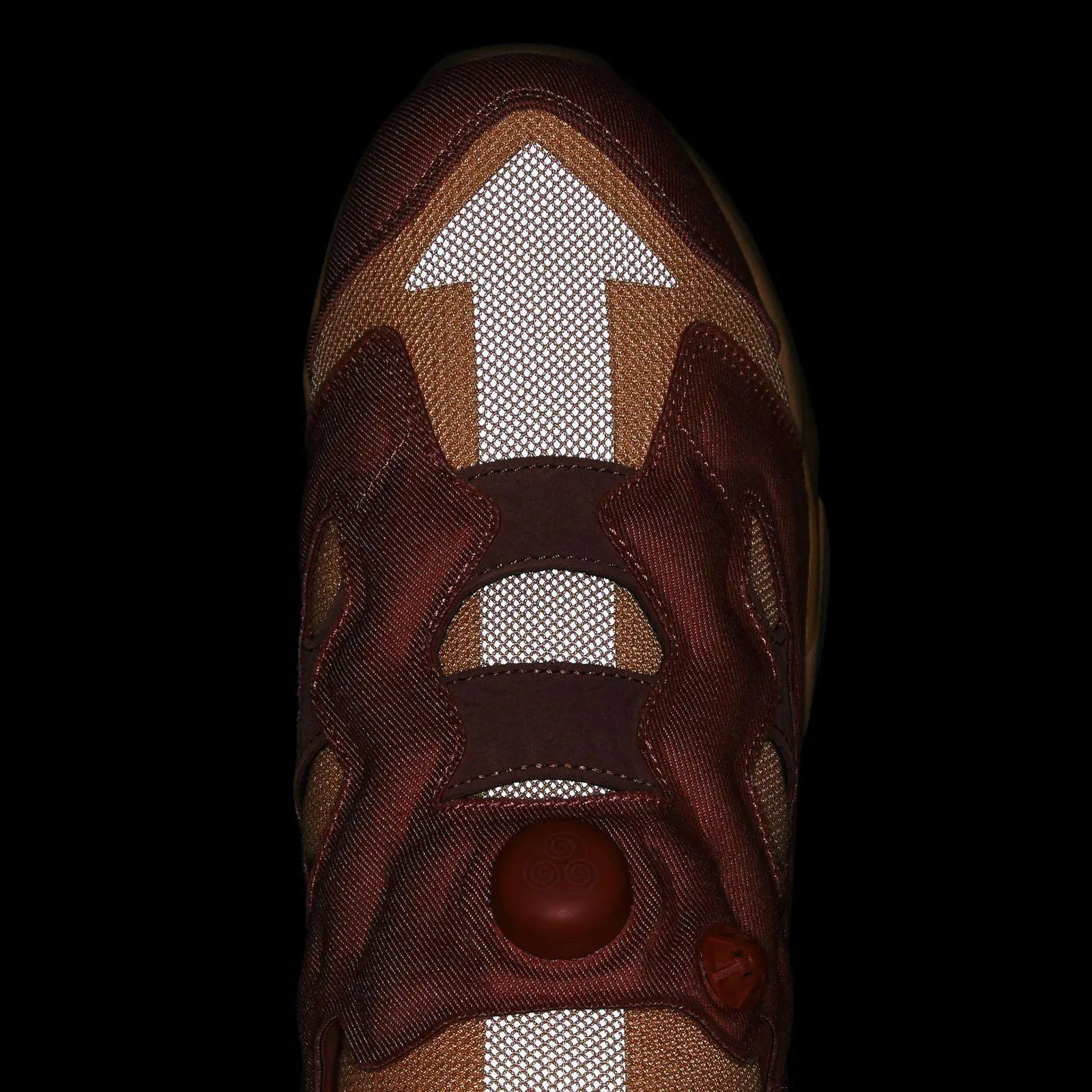 Top-down detail in dark lighting, white reflective arrow on toe, pump button with spiral, Aang