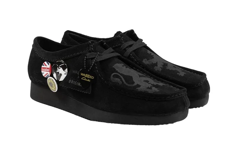 Pair in three-quarter view, black suede with Union Jack and other badges, on white, x Wasted Paris