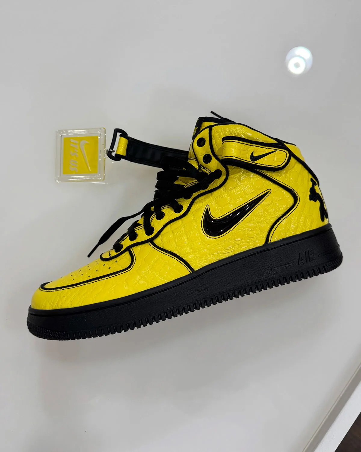 Lateral view of yellow croc-embossed mid with black sole and swoosh, clear "It's us" tag, Force 1 Mid