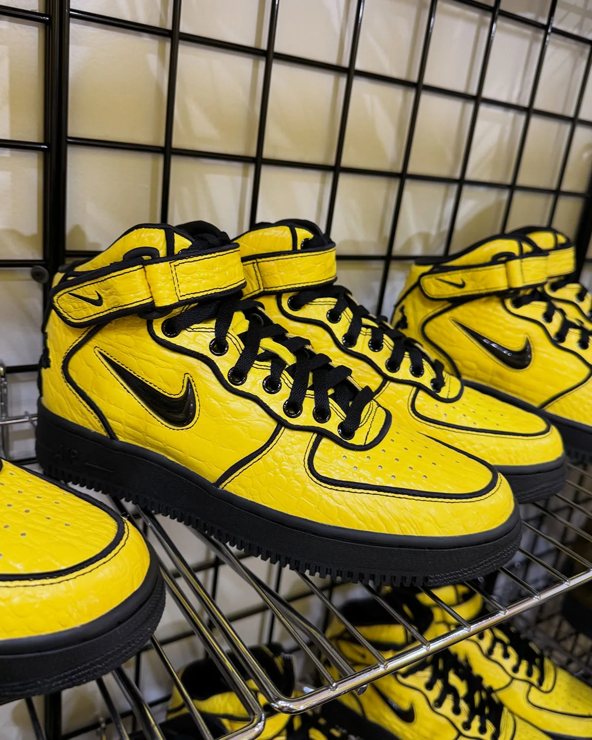 Lateral three-quarter view on a wire shelf, yellow croc leather, black laces and sole, Force 1 Mid