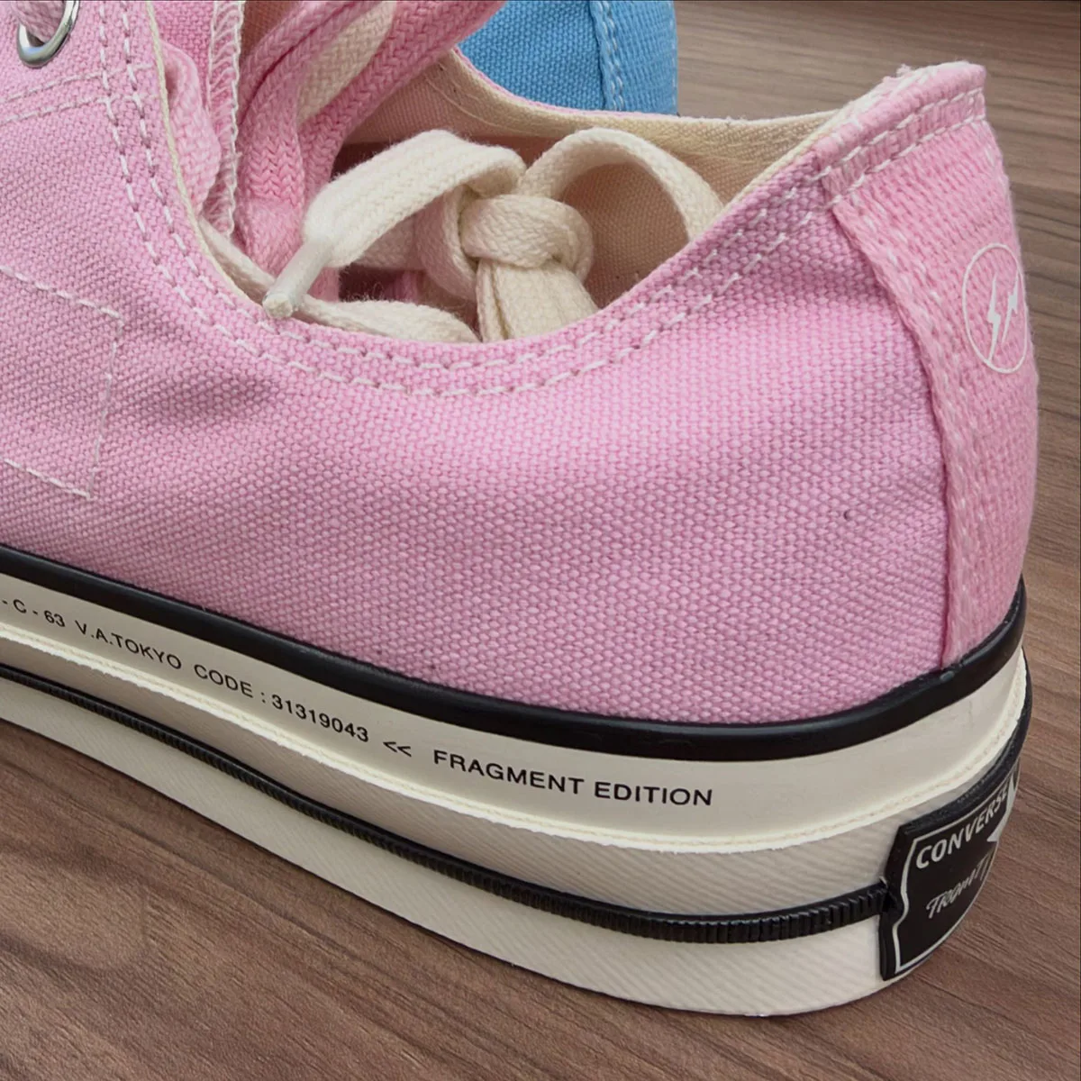 Heel detail of pink canvas shoe with lightning logo and "Fragment Edition" text on cream midsole, Chuck Taylor Low