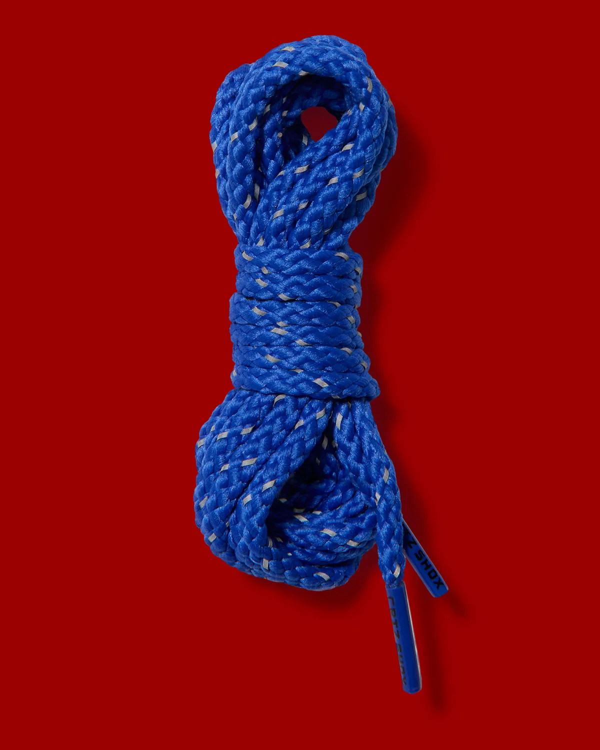 Coiled blue laces with grey reflective flecks and black printed tips on a red background, Game Royal