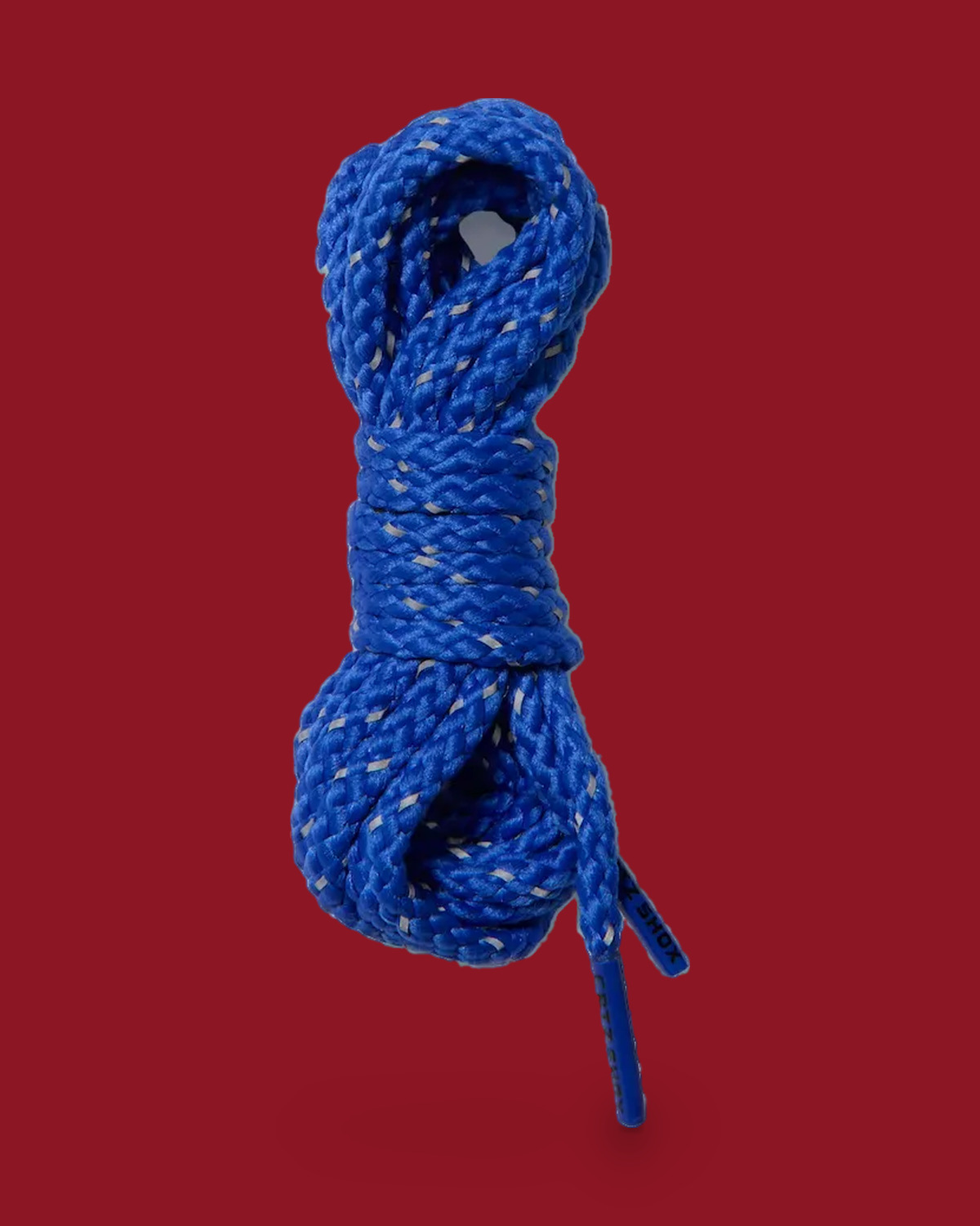 Coiled blue laces with grey reflective flecks, black text on the tip, on red background, Game Royal