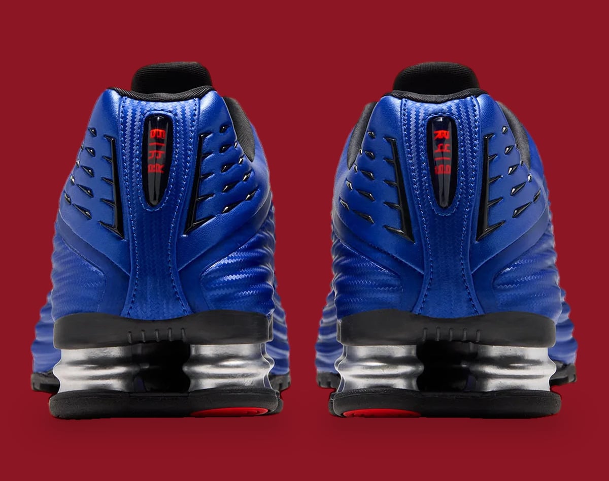 Heel view of pair: blue uppers, red text in heel window, silver springs, black soles, Game Royal