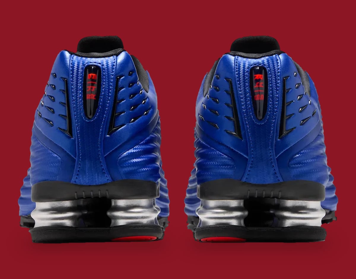 Heel view of pair: blue uppers, red text in heel window, silver springs, red outsole pods, Game Royal