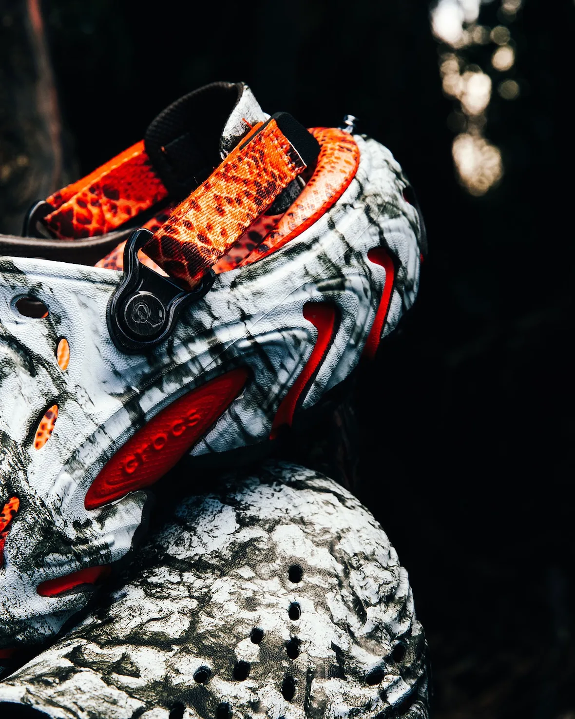 Close detail of marbled clog heel, orange snakeskin strap, black pivot with logo, orange crocs-embossed pod, Watch Your Step