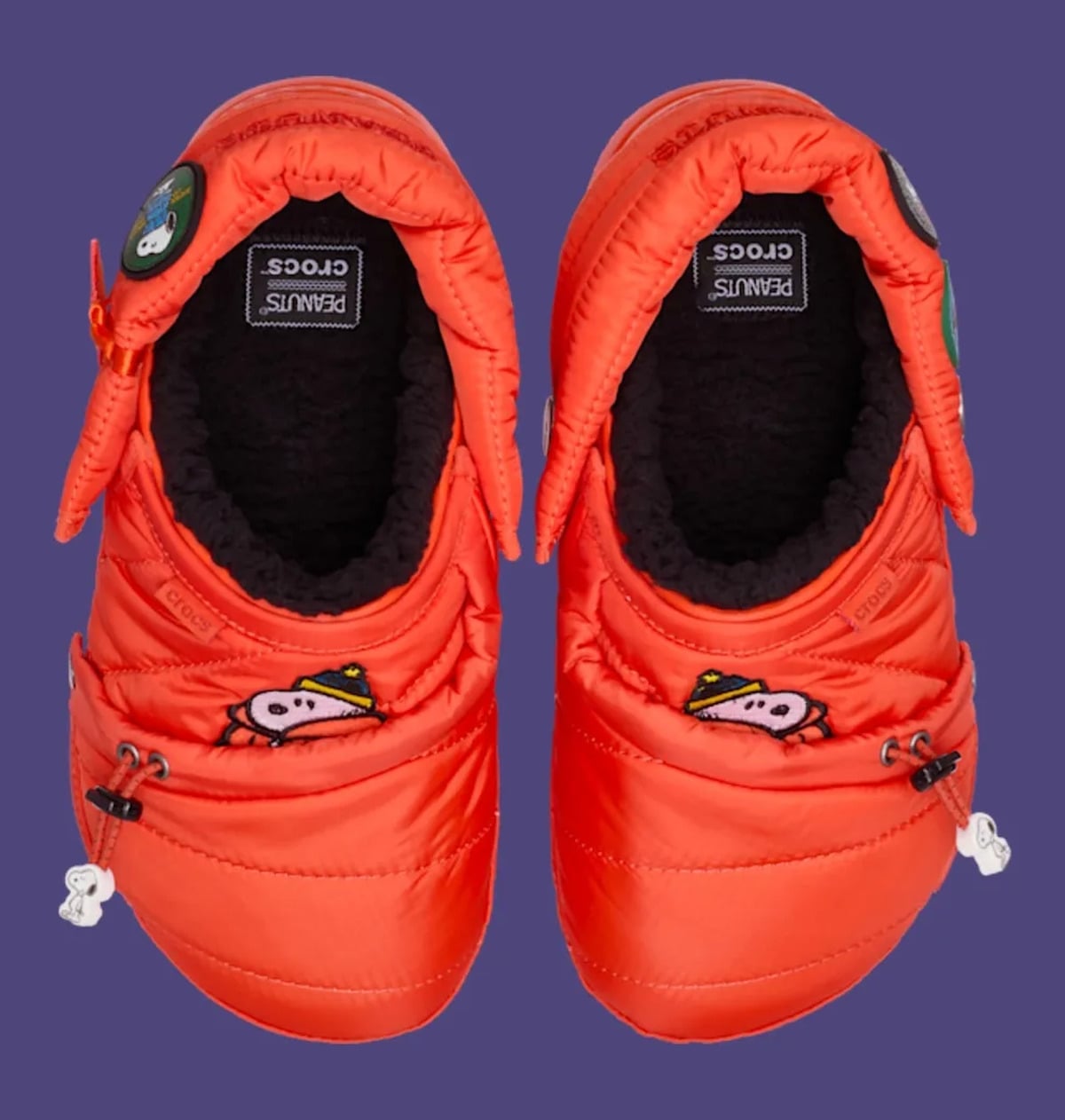 Top-down pair showing black fleece lining, Peanuts x crocs insole label, Snoopy toggles, Classic Lined Clog