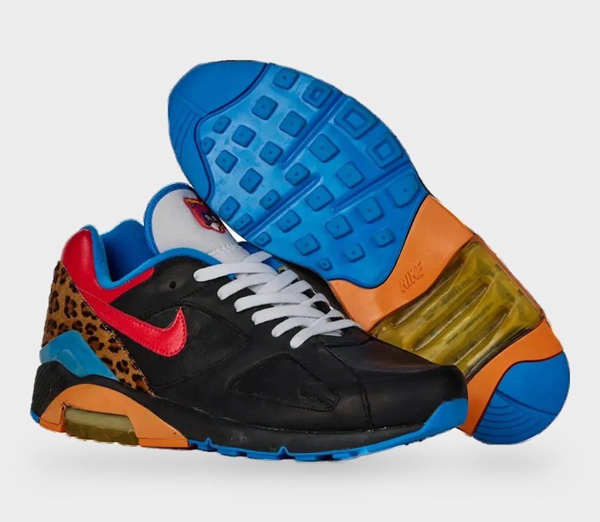 Pair, one shoe upright and one showing blue outsole; black leather, red swoosh, leopard heel, StockX LISTED Collection