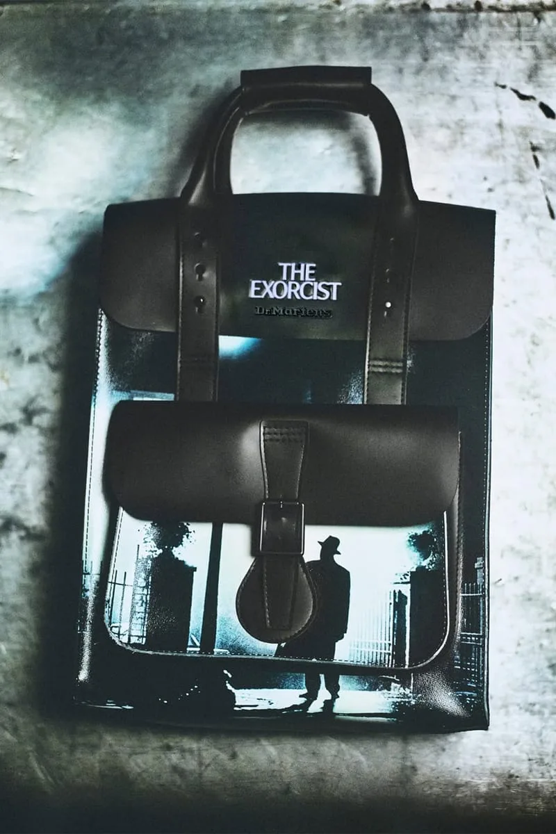 Top-down view of black leather bag with silhouette-in-doorway print and The Exorcist logo on flap, The Exorcist