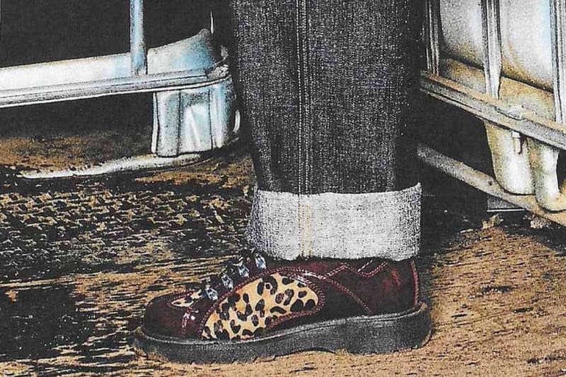 On-foot view of burgundy leopard-print boot with rolled grey denim cuff on dirt ground, x Brain Dead