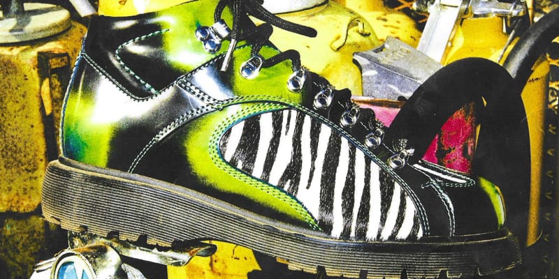 Close-cropped lateral view of green and black zebra-print boot with chunky sole, yellow cylinders behind, x Brain Dead