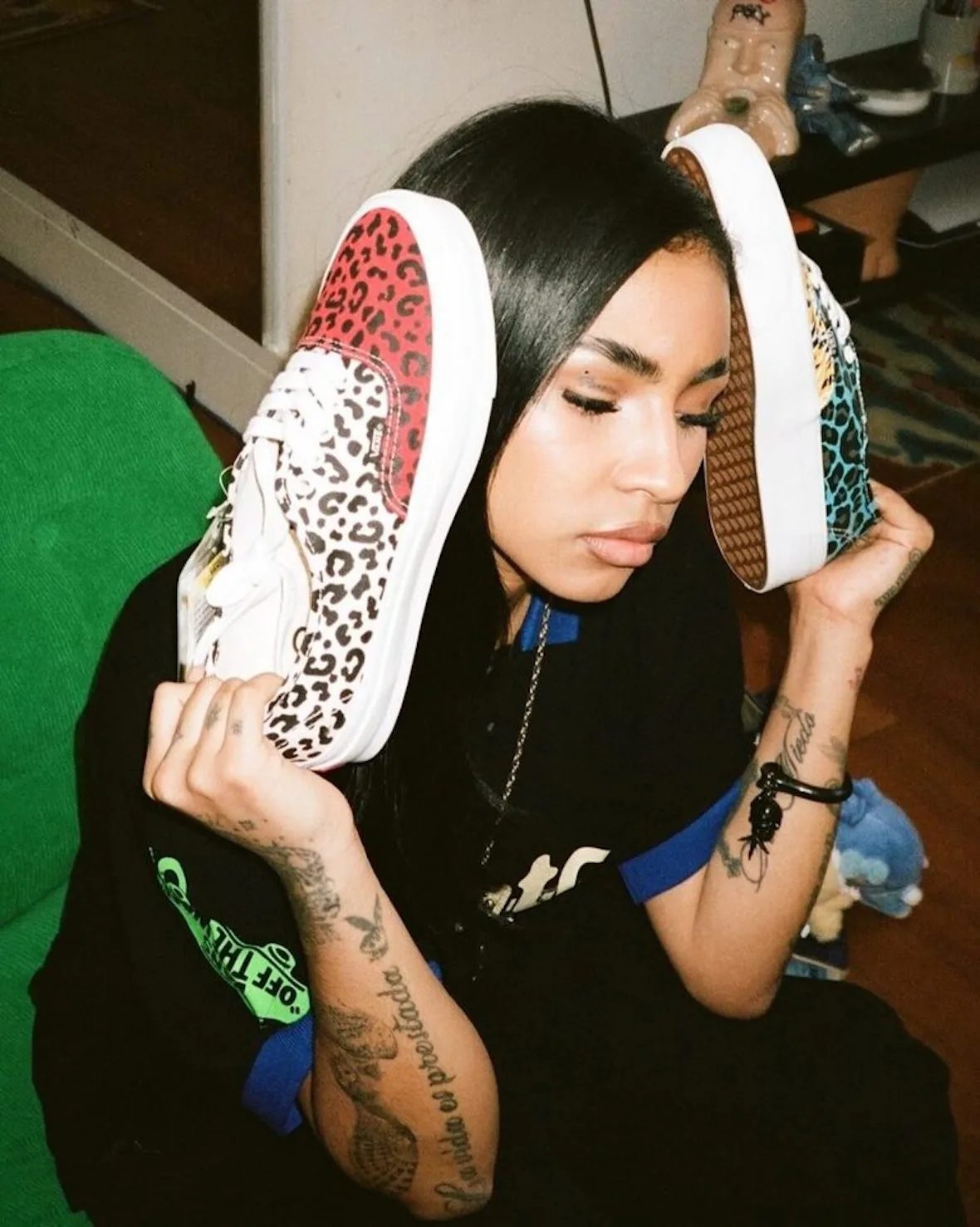 On-foot style shot of a woman holding red and cream leopard-print sneakers and a teal pair beside her head, Cheetah Print