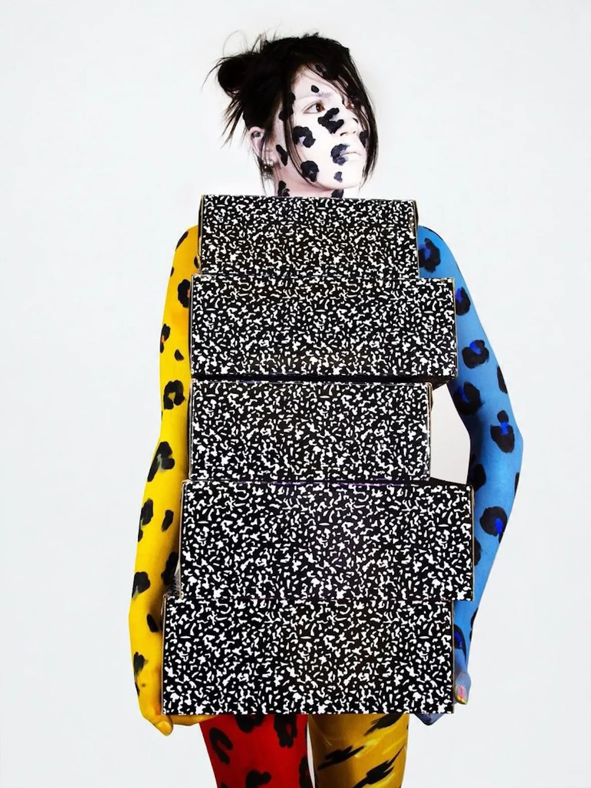 Body-painted model in yellow, blue and red leopard spots holding a stack of black-and-white speckled shoe boxes, Cheetah