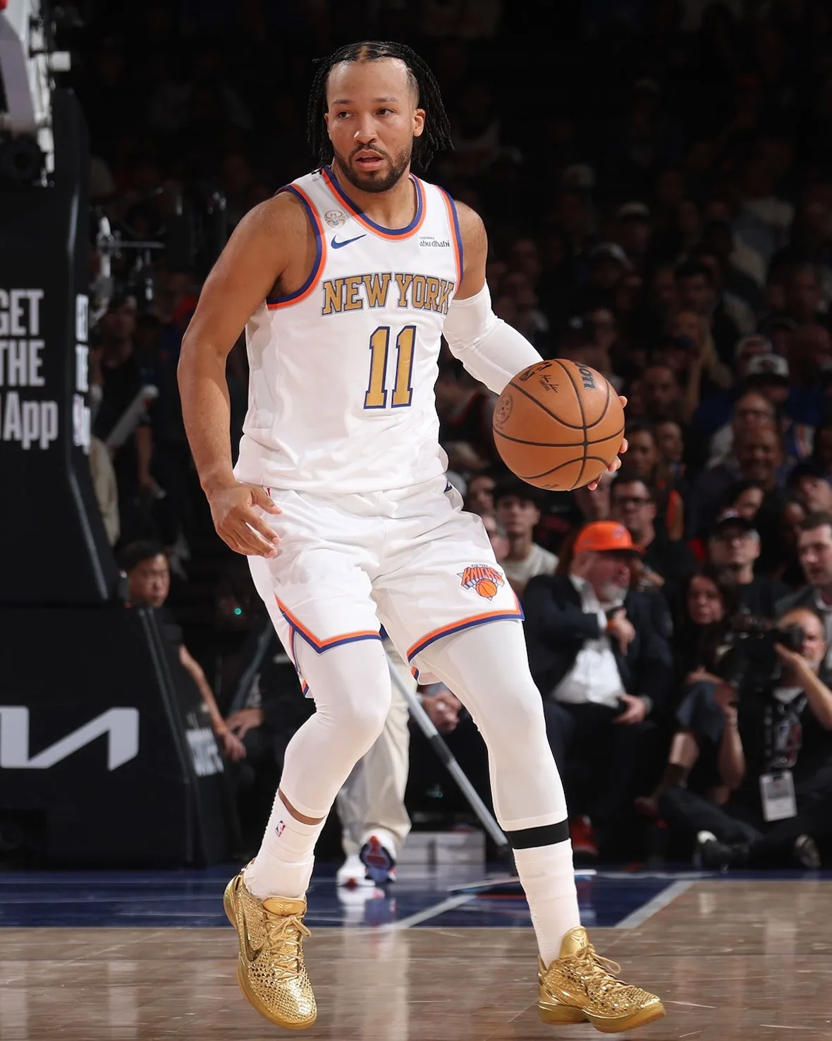 Player in white New York #11 jersey dribbling a basketball, wearing gold shoes, with a dark crowd behind, Ring Night